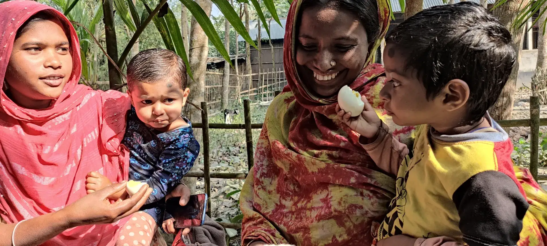 Smiling mothers holding young children in warm clothes.