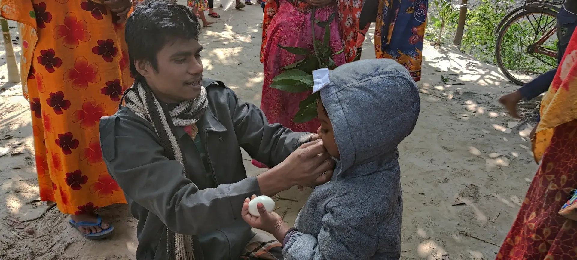 A volunteer kneels to talk with a small child in a new winter jacket.