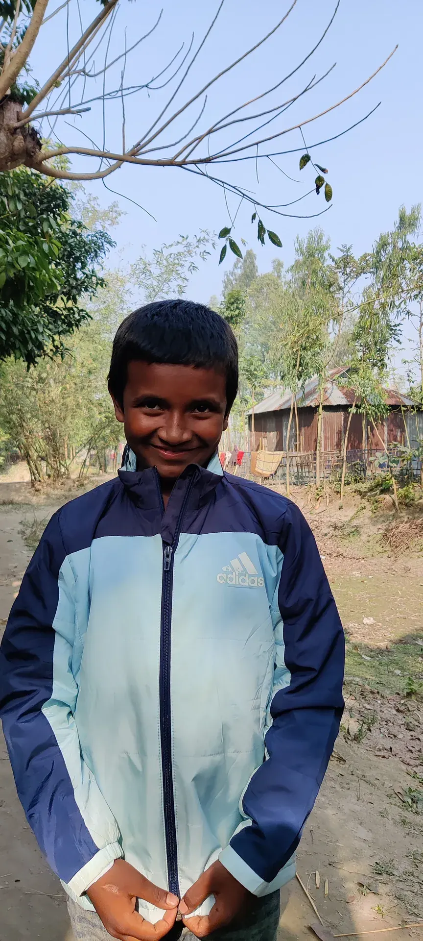 A boy from the village in a winter jacket from the clothes drive.